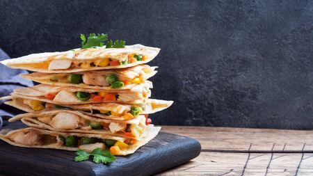 Triangular slices of a Mexican quesadilla with the sauce. The traditional dish of Mexico is tortillas stuffed with meat and vegetables copy space.の写真素材