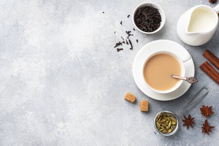 Indian drink masala tea with milk and spices. Cardamom sticks cinnamon star anise cane sugar. Concrete grey table copy space.の写真素材