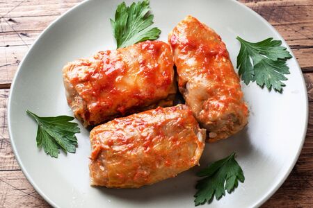 Cabbage rolls with beef, rice and vegetables on the plate. Stuffed cabbage leaves with meat. Wooden background.の写真素材