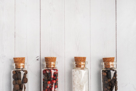 Spices black and red pepper and salt in glass flasks on a white woodenの写真素材