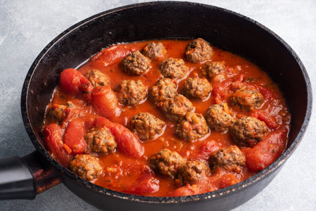 Delicious juicy Meatballs in tomato sauce are cooked in a cast iron pan. Close up Concrete background.の写真素材