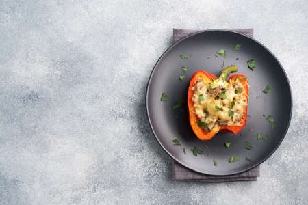 Stuffed sweet pepper with rice mushrooms and cheese with herbs. Baked halves of red pepper with filling. Gray concrete background Copy space,の写真素材