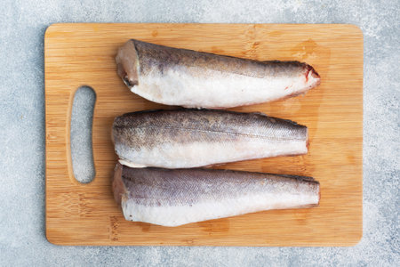Raw hake fish carcass on a wooden chopping Board. top view Copy space.
