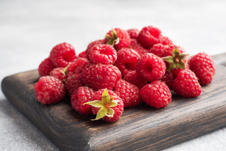 A pile of fresh juicy raspberries on a wooden Board, copy space