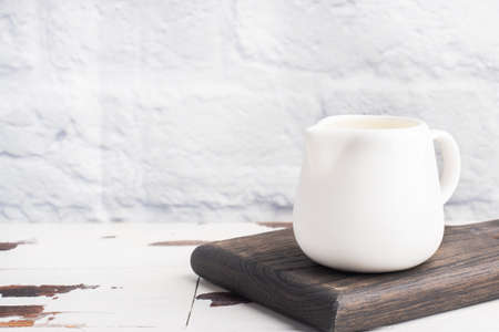 White ceramic milk jug with fresh milk on a gray background. Copy spaceの写真素材
