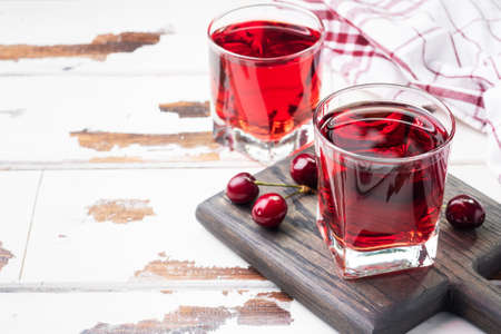 Cherry juice in glass glasses with fresh cherry berries. White background. copy spaceの写真素材