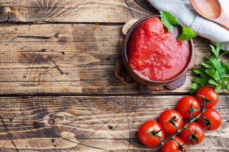 Tomatoes in their own juice or Tomato paste in a wooden bowl and fresh tomatoes on a rustic wooden table Copy spaceの写真素材