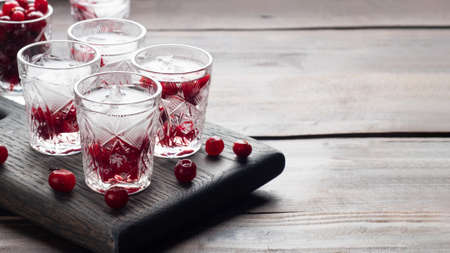 Stacks of vodka and cranberries on a wooden stand and background. Copy of the space. Bar alcoholic beverage tinctureの写真素材