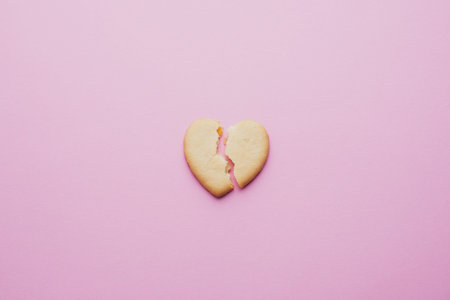 Heart shaped cookies, a cracked heart on a pink background, the concept of a broken relationship