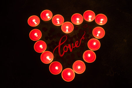 Red candles in the shape of heart on black background, concept of Valentine's Dayの写真素材