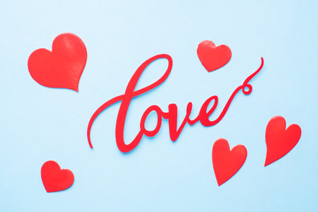 The word Love and red hearts on a blue background, top view. Holiday card for Valentine's Day. Flat layの写真素材
