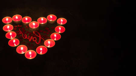 Red candles in the shape of heart on black background, concept of Valentine's Dayの写真素材