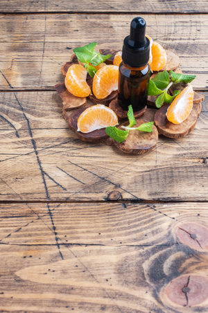 Aromatic tangerine oil in a dark bubble, cosmetic oil from Mandarin on a wooden background, copy spaceの写真素材