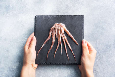 Raw squid tentacles on a black slate board. copy space Top view. Gray backgroundの写真素材