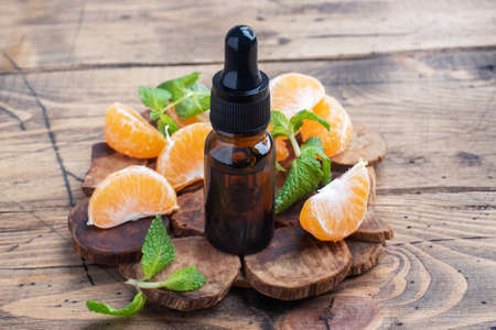 Aromatic tangerine oil in a dark bubble, cosmetic oil from Mandarin on a wooden background, copy spaceの写真素材