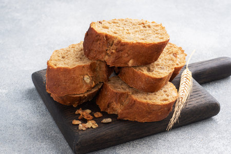 Sliced rye baguette on a gray background with cereals. Whole grain bread, a healthy food concept....