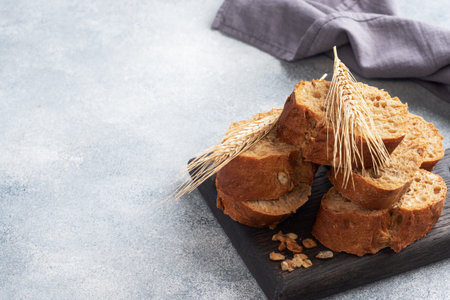 Sliced rye baguette on a gray background with cereals. Whole grain bread, a healthy food concept....