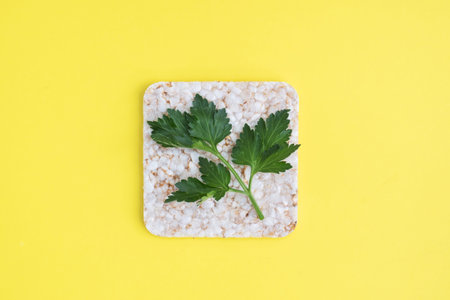 Healthy snack Crunchy crispbread with fresh parsley leaves. Yellow background, copy space