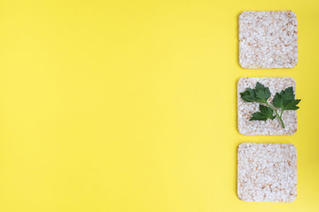 Healthy snack Crunchy crispbread with fresh parsley leaves. Yellow background, copy space