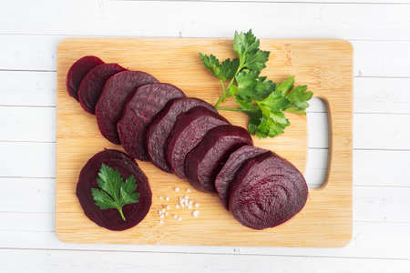 Slices of boiled beetroot on a cutting Board with parsley leaves on a wooden rustic background. Copy space,の写真素材
