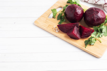 Boiled beets whole and cut on a cutting Board with parsley leaves on a white background. Copy space,の写真素材