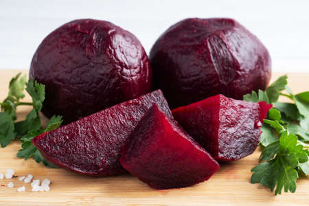 Boiled beets whole and cut on a cutting Board with parsley leaves on a white background. Copy space,の写真素材