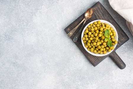 Canned peas in a plate on a wooden Board. Copy spaceの写真素材