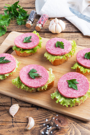 Sandwiches with lettuce leaves and sliced salami sausage on a wooden Boardの写真素材