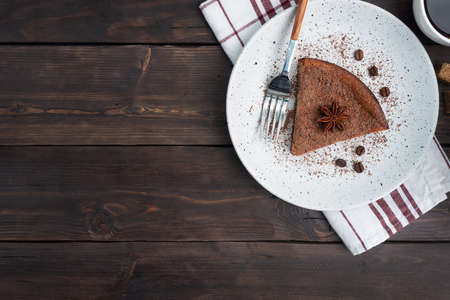 Slice of chocolate curd casserole on a plate, a portion piece of cake with chocolate and coffee. Dark wooden rustic background top view, copy spaceの写真素材