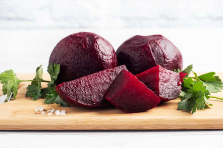 Boiled beets whole and cut on a cutting Board with parsley leaves on a white background. Copy space,の写真素材