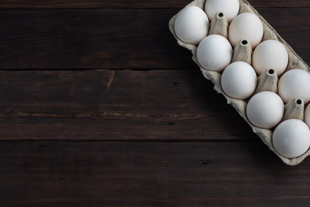 Fresh chicken eggs in a package, raw eggs in a white shell in a box. Top view copy space, wooden...