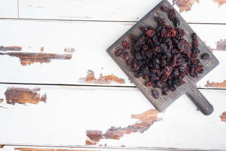 Dried raisins from dark grapes in a plate on a wooden chopping boardの写真素材