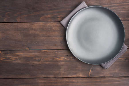 Empty black plate on wooden rustic background. Top view with copy space