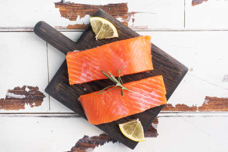Salmon fillet, red salted fish on a wooden chopping Board. Lemon, rosemary spices Copy space.の写真素材
