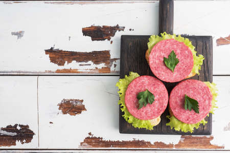 Sandwiches with lettuce leaves and sliced salami sausage on a wooden Board Copy space top viewの写真素材