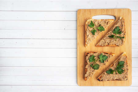 Sandwiches crispy toast and chicken liver pate with parsley leaves on a wooden cutting board. Copy spaceの写真素材