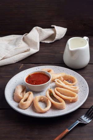 Fried squid rings with tomato sauce and lemon. Dark wooden background copy spaceの写真素材