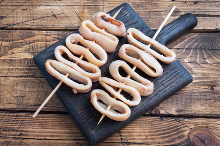 Fried squid rings on a skewer with tomato sauce and lemon. Dark wooden background copy space. Top viewの写真素材