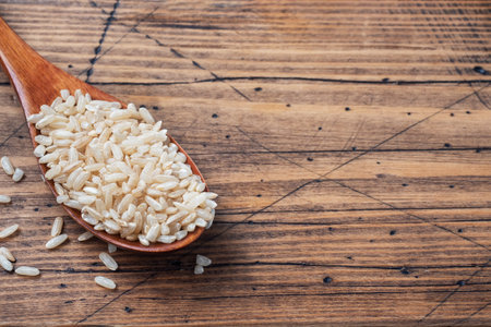Brown rice raw long grain in a spoone, wooden background copy spaceの写真素材