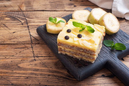 Banana sponge cake with nuts and chocolate drops. Delicious sweet dessert for tea, wooden background...