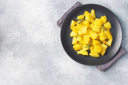 Delicious baked potatoes with spices cheese and rosemary on a black ceramic plate, a gray concrete background, copy spaceの写真素材