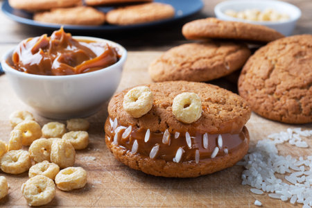 Cookies with cream paste in the shape of monsters for Halloween celebration. Funny homemade faces made of oatmeal cookies and boiled condensed milkの写真素材