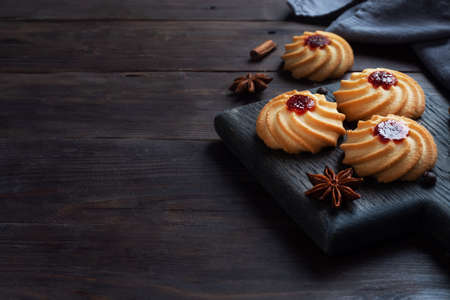 Kurabye shortbread cookies with berry jam in a black plate. Delicious dessert, dark wooden background with copy spaceの写真素材