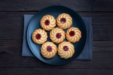 Kurabye shortbread cookies with berry jam in a black plate. Delicious dessert, dark wooden background with copy spaceの写真素材