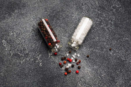 Spices black and red pepper and salt in glass flasks on a dark background with copy spaceの写真素材