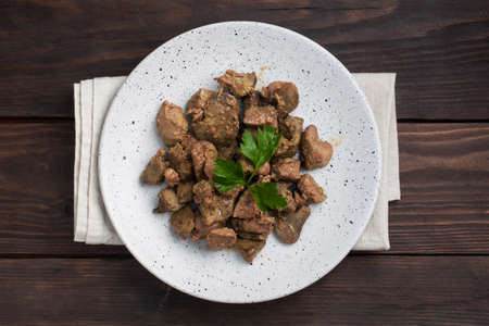 Fried or baked chicken liver with onion and sauce, green parsley leaves on a plate. Meat dish enriched with ironの写真素材