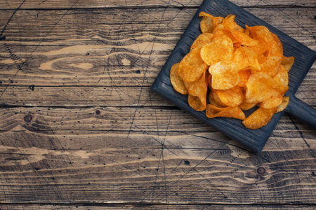 Crispy potato chips, wooden background texture of golden chips. fast food snack. copy spaceの写真素材