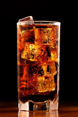 Glass of cold cola with the ice on a tableの写真素材