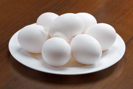White raw eggs on a plate, wooden backgroundの写真素材