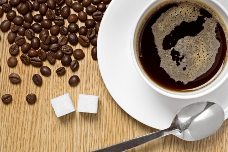 Coffee cup, beans and lump sugar on a table, studio shotの写真素材